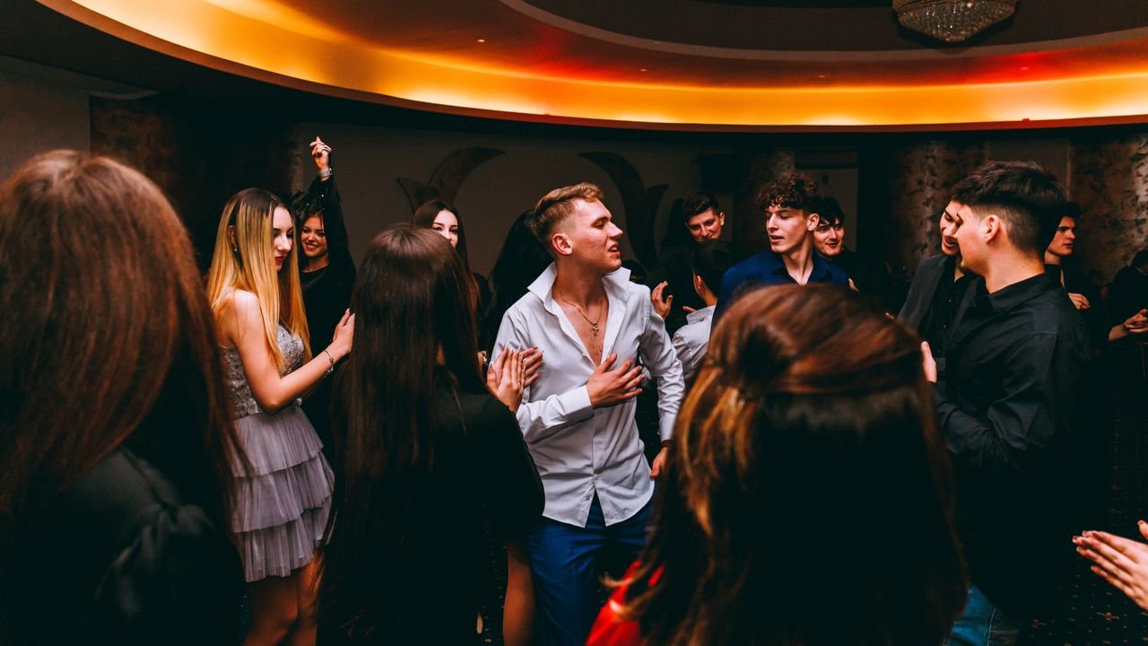 Crafting Captivating Headlines: Your awesome post title goes here A lively group of teenagers dancing indoors at a party with vibrant lighting and joyous expressions.
